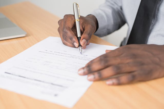 person%20signing%20a%20document%20with%20a%20silver%20pen